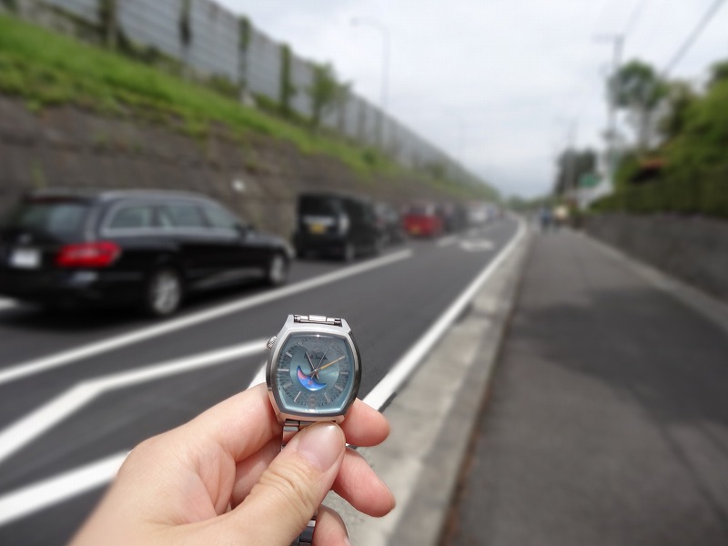 腕時計と駐車待ちの車の列
